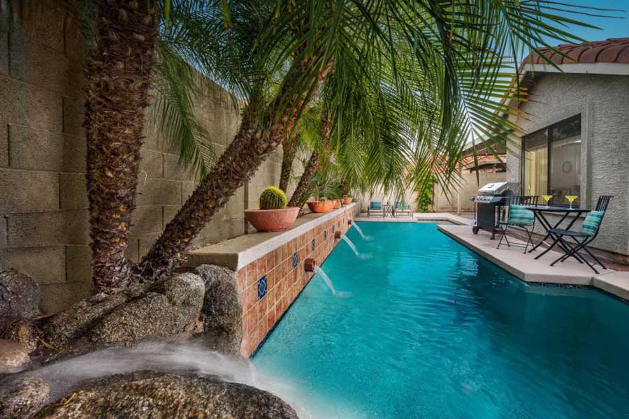backyard pool with fountains, palm trees and patio furniture on a monthly rental