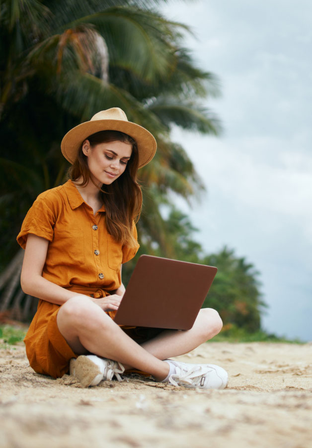 monthly vacationer sitting on a beach and working on a laptop