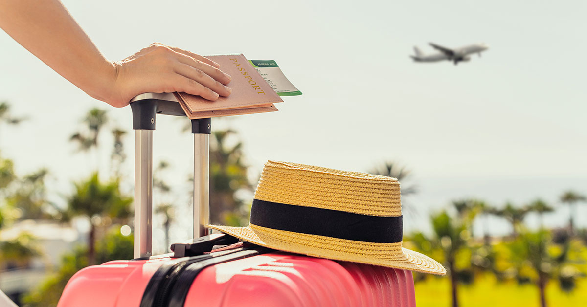 person with hand on suitcase and tickets in hand with airplane in background