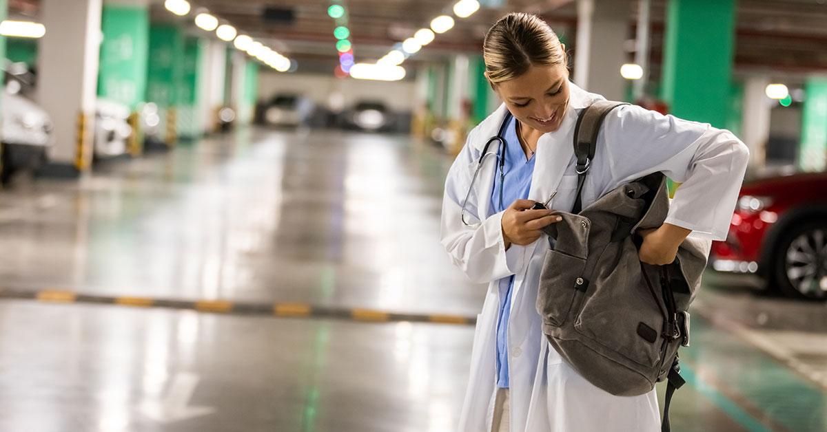 nurse looking in backpack while in parking garage