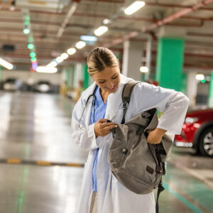 nurse looking in backpack while in parking garage