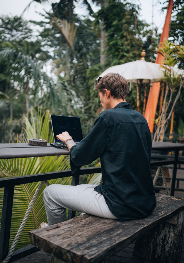 man on computer in tropical location
