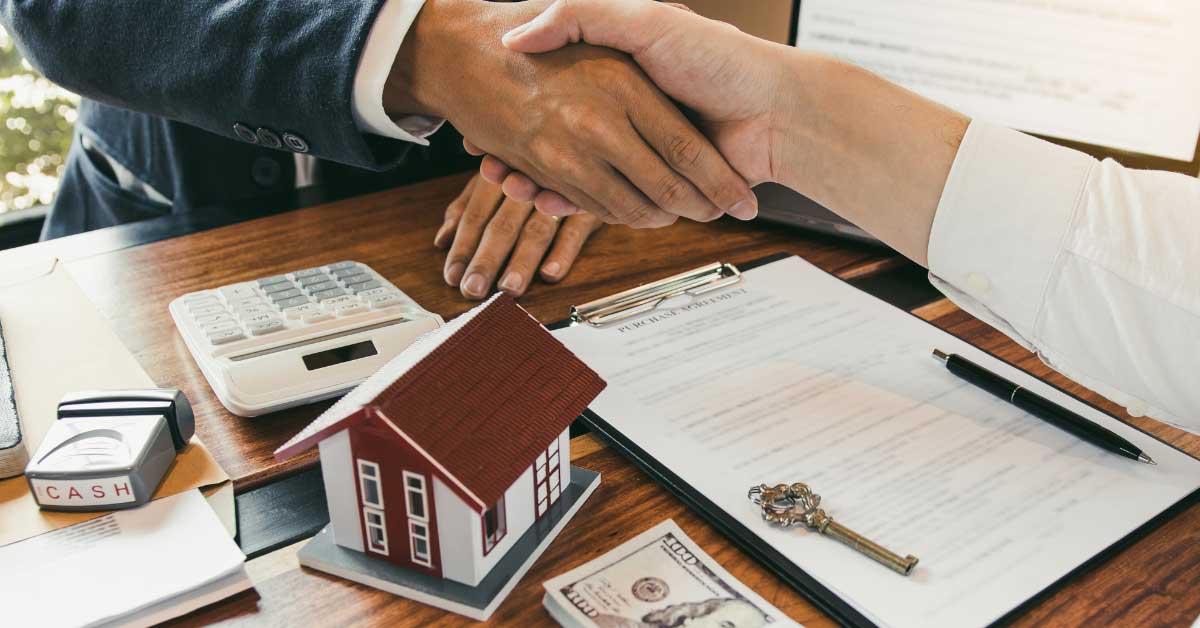 shaking hands over paperwork with key and small house on it