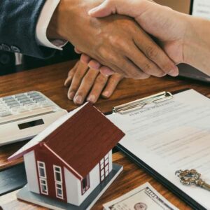 shaking hands over paperwork with key and small house on it