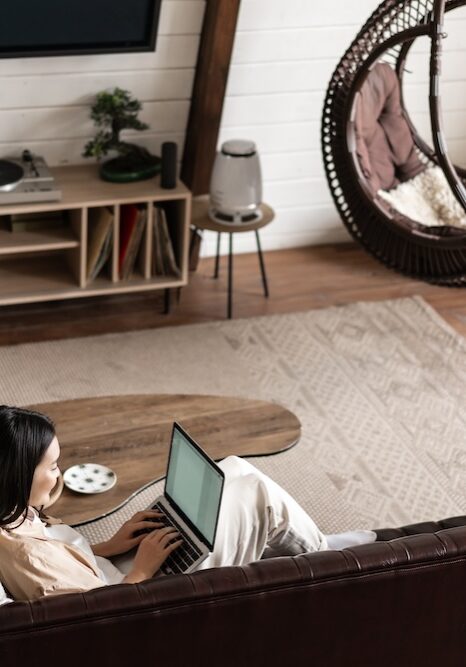 Portrait of asian woman working from home on laptop computer, sitting on couch and resting. Korean girl with pc in living room.