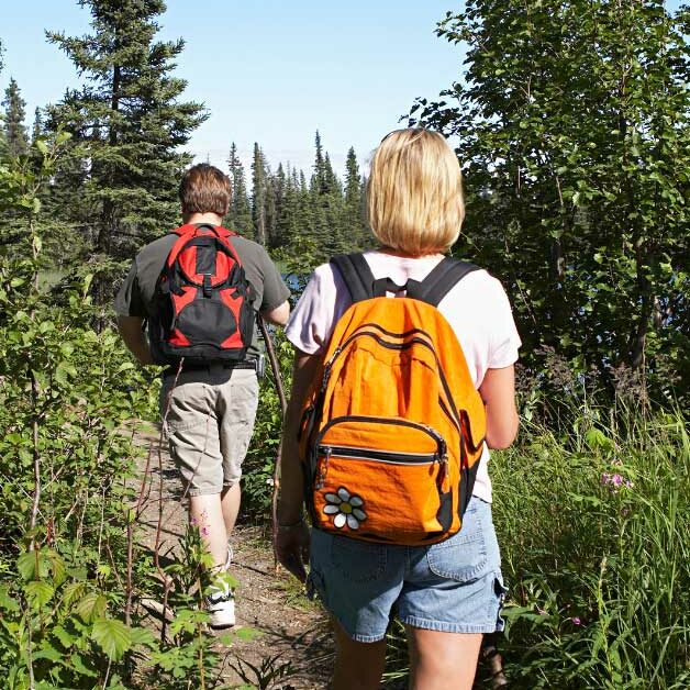 couple hiking in forest wearing backpacks