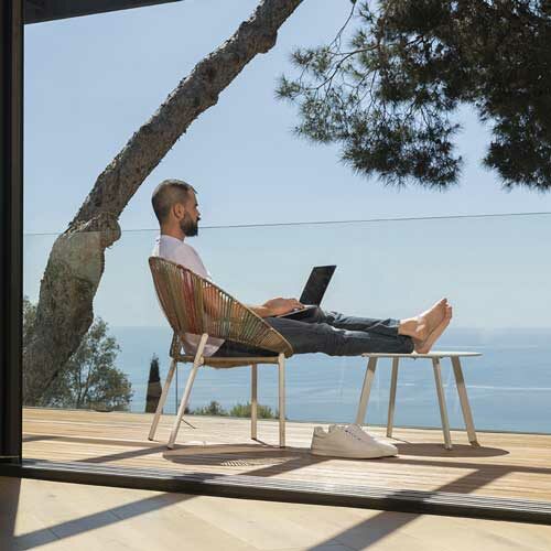 man sitting on deck with laptop working overlooking water